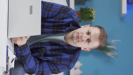Vertical-video-of-Home-office-worker-man-looking-dull-at-camera.